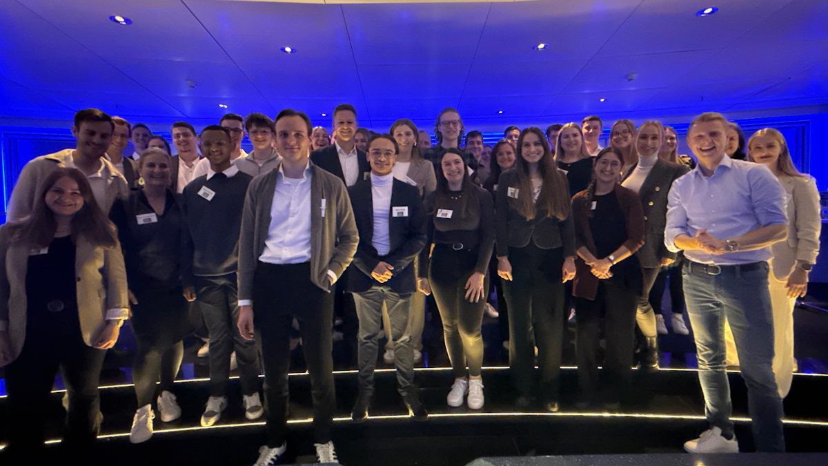 Gruppe von jungen Menschen; Teilnehmer des Raiffeisen-Camps 2025 vor blauem HIntergrund, dem Licht am Abend in der Skylobby der DZ BANK Frankfurt